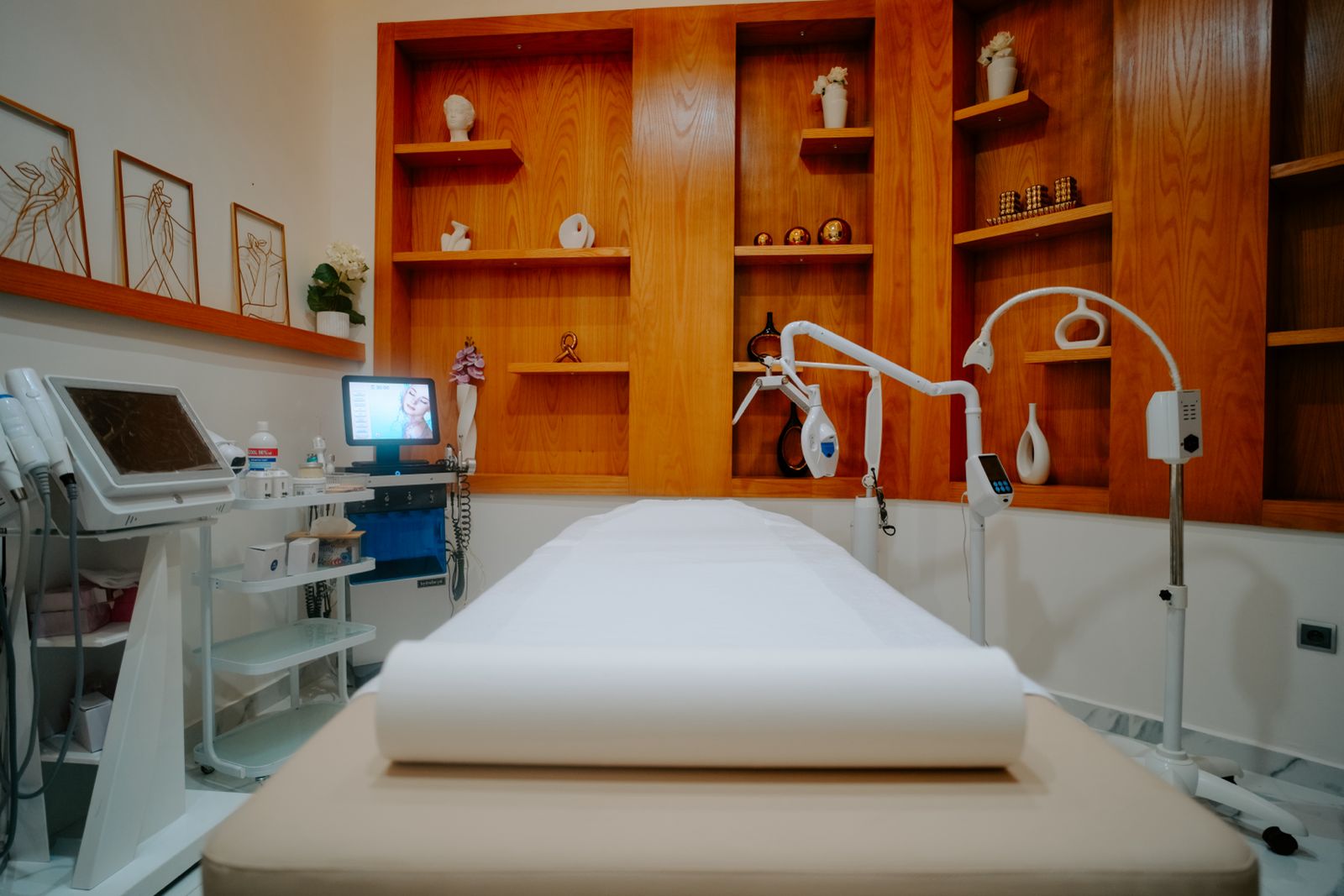Cabine de soins de Bloom Clinic, table préparée et appareils de médecine esthétique alignés le long du mur